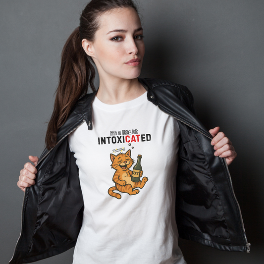 Woman wearing a white t-shirt with a cat-themed graphic design and text, standing against a dark background.